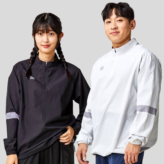 A male and a female model wearing athletic clothing, the female in a black jacket and the male in a white jacket with gray stripes, both displaying a team logo on the chest.